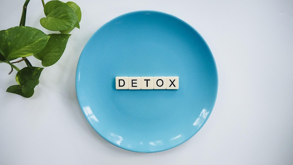 The phrase "detox" is artistically presented on a vibrant blue plate, emphasizing health and wellness.