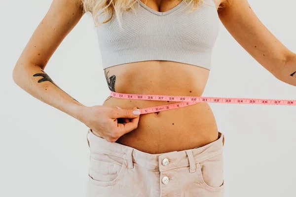 Woman using measuring tape around her waist