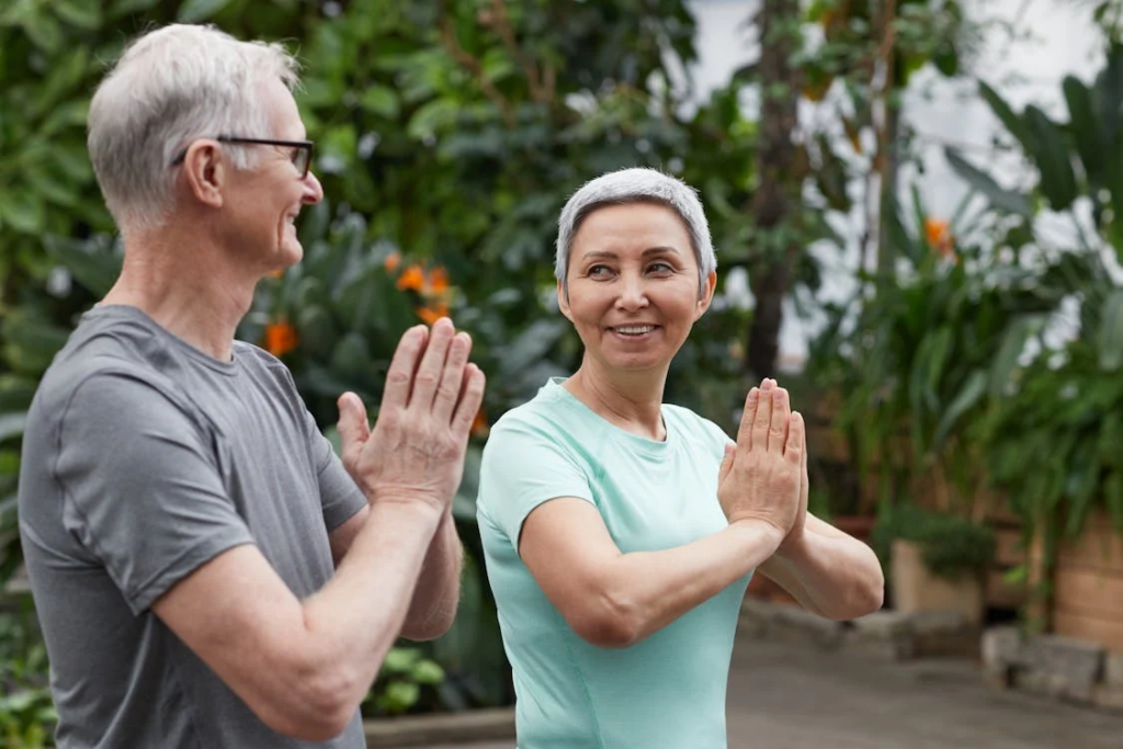 An older couple practicing yoga in a serene garden, highlighting the benefits of lifestyle factors in healthy aging.