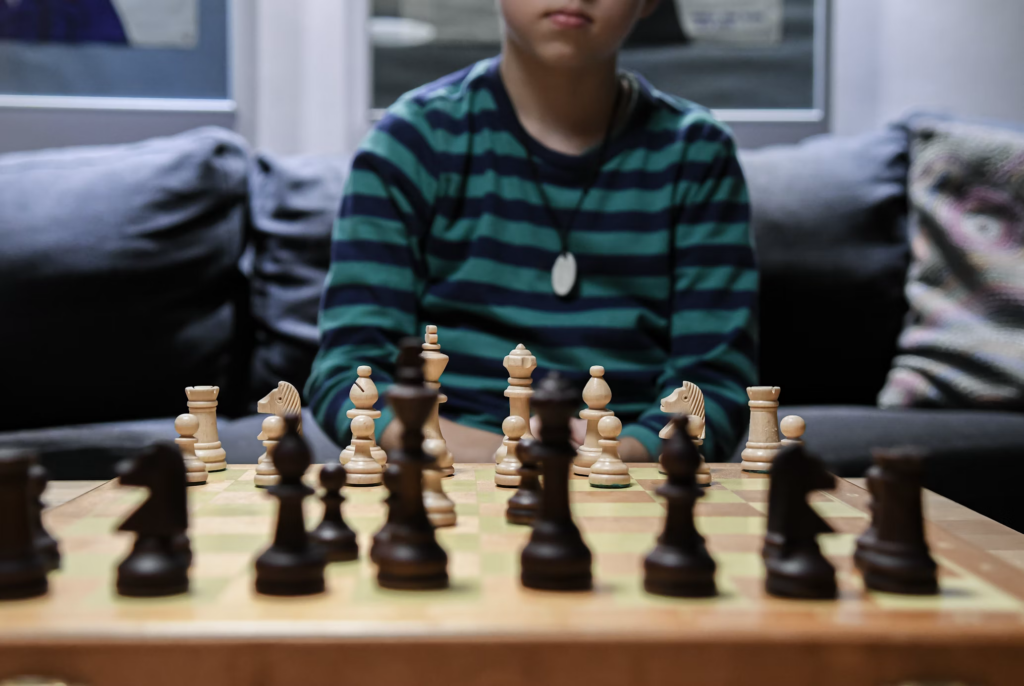 A young boy on a couch contemplates his next move on a chess board, illustrating the importance of strategy and foresight.