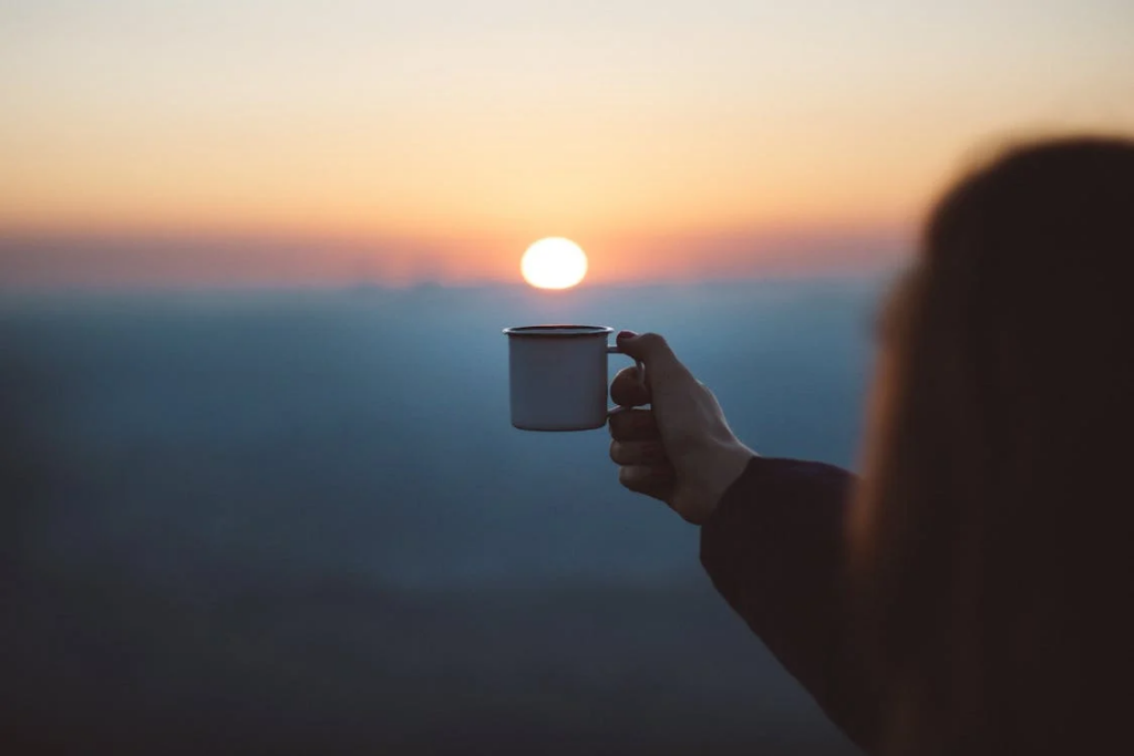 A silhouette of an individual with a coffee cup, illuminated by sunlight, symbolizing the transition from the 40s to the 60s