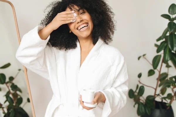 woman removing makeup with cotton pad and makeup remover