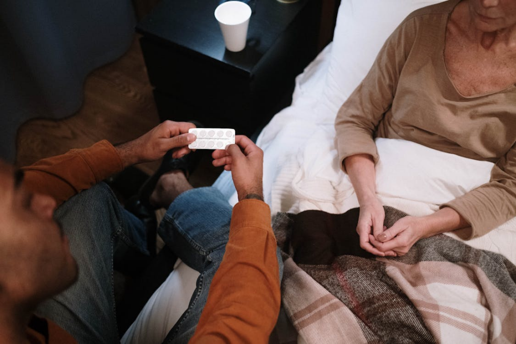 Man Giving Medicine to Elderly Woman in Bed