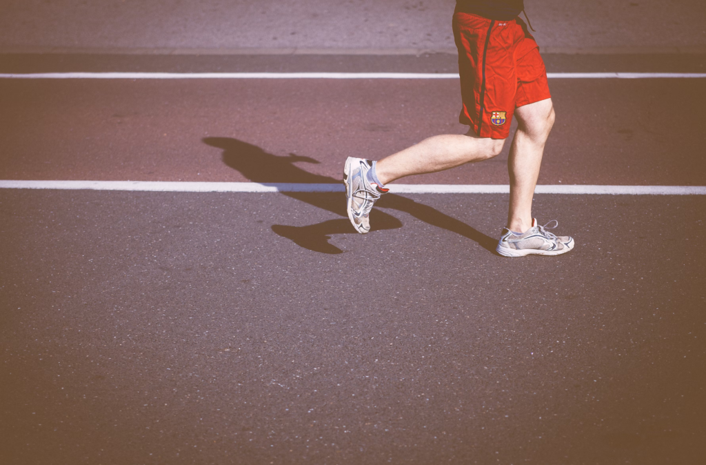 Person running on a track. Red shorts with a logo. Illustrates movement's link to reduced dementia risk.