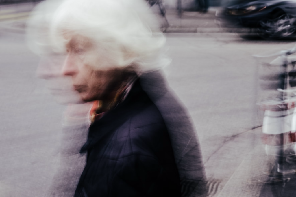 An elderly woman strolls down the street, embodying the benefits of movement for cognitive health and dementia prevention.