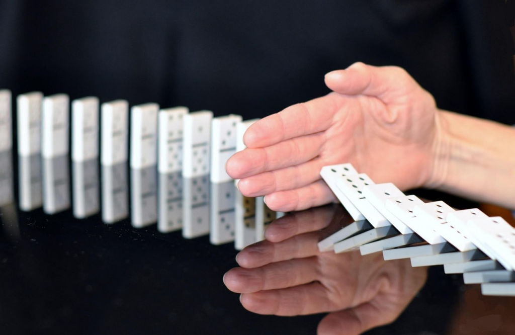 a hand stopping a domino effect