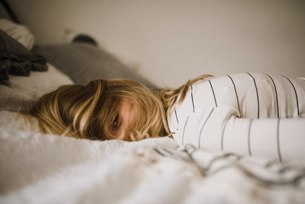 A woman lies on her bed, resting her head on a pillow, reflecting the challenges of sleep problems at night.
