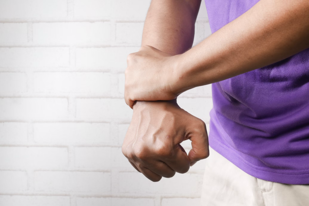 A man in a purple shirt holds his wrist, symbolizing the connection between depression and chronic pain 