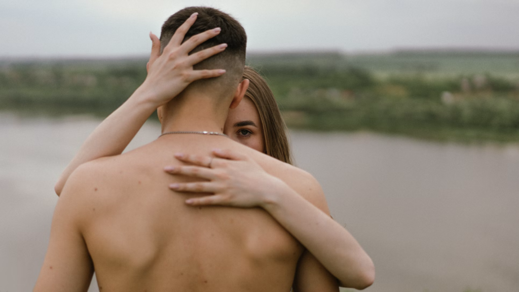 A couple shares a warm hug by the river, representing support and intimacy in the face of struggles such as depression.
