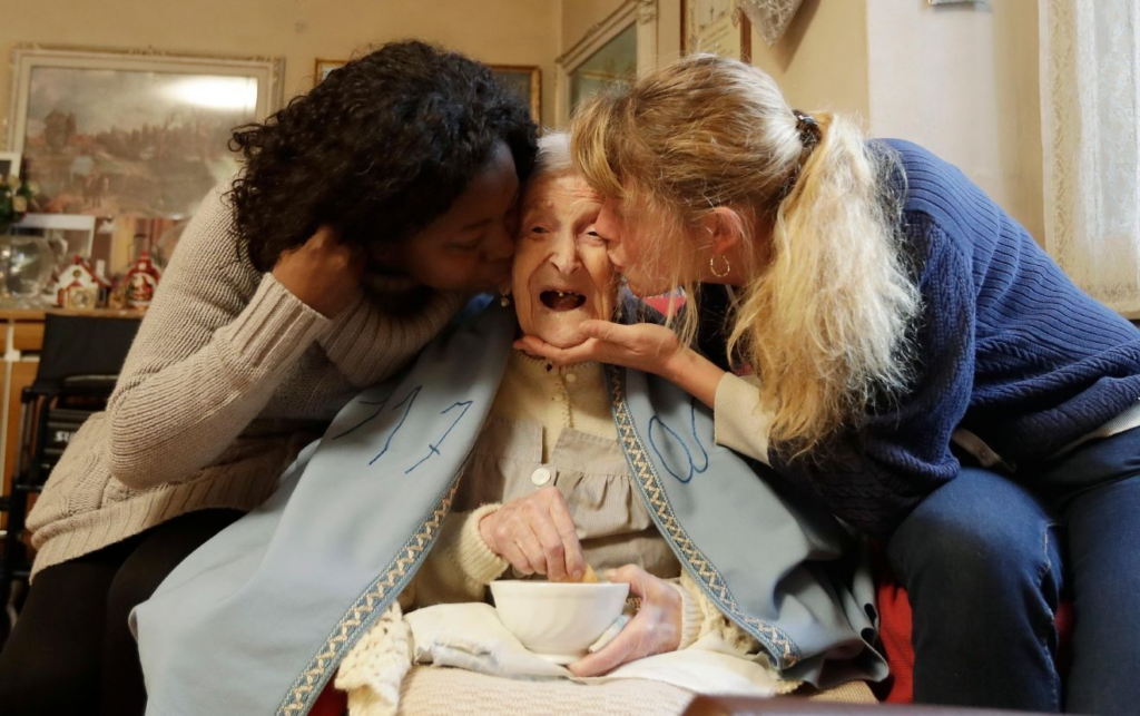 Emma Morano receiving a kiss on her check from two woman