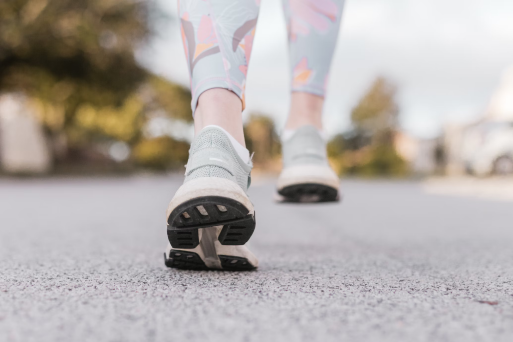 A person wearing sneakers strolls along the street, promoting heart health and cognitive function through walking.