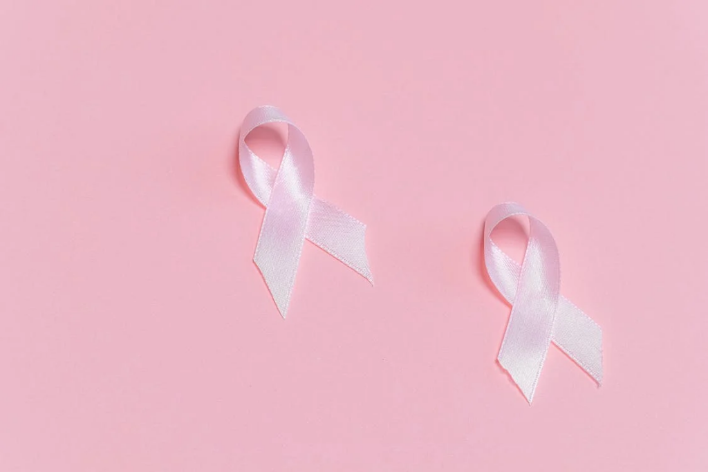 Breast cancer awareness ribbon on a pink background, symbolizing the importance of walking for cancer risk reduction.