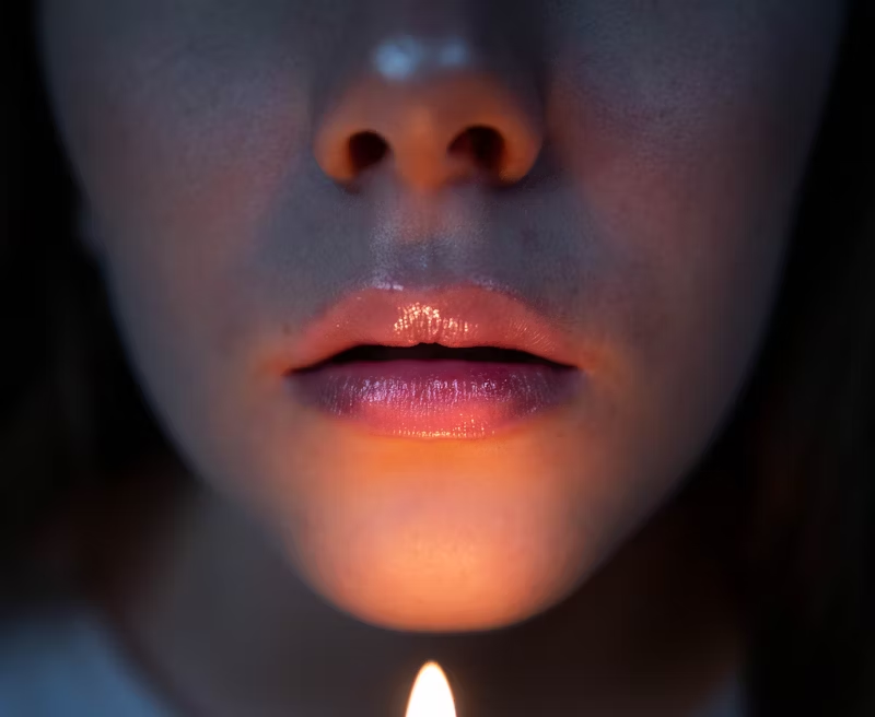 a flame beneath someone's mouth