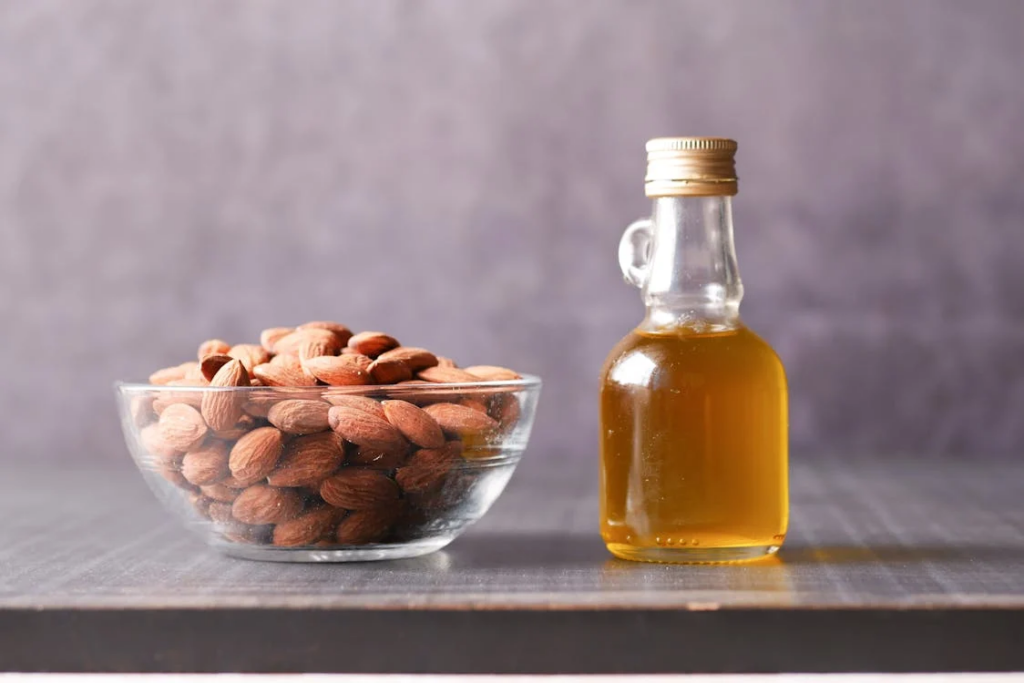 Almonds on Clear Glass Bowl Beside Bottle with Yellow Liquid