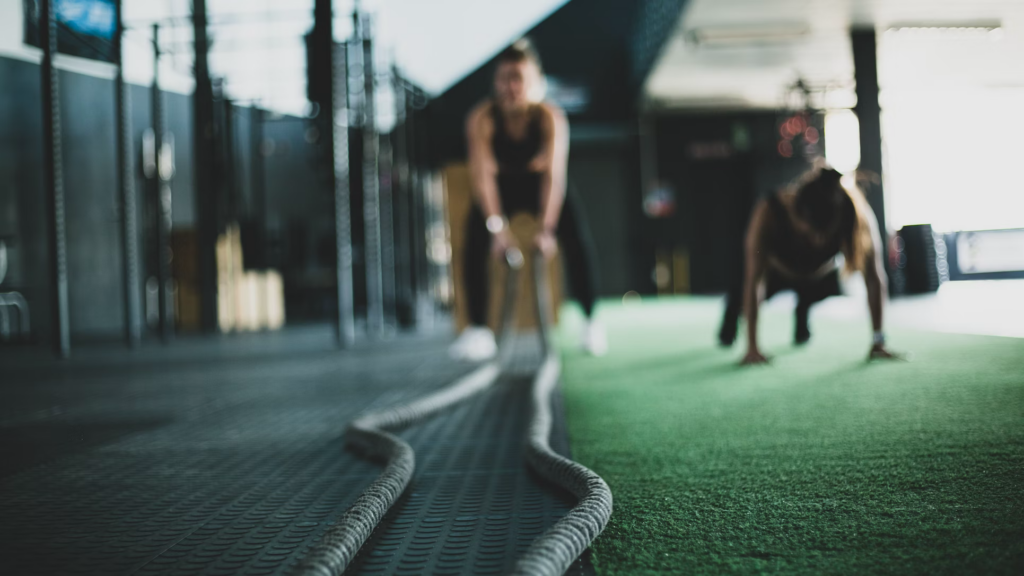 Two individuals perform push-ups on a rope in a gym, showcasing a HIIT workout beneficial for heart health.