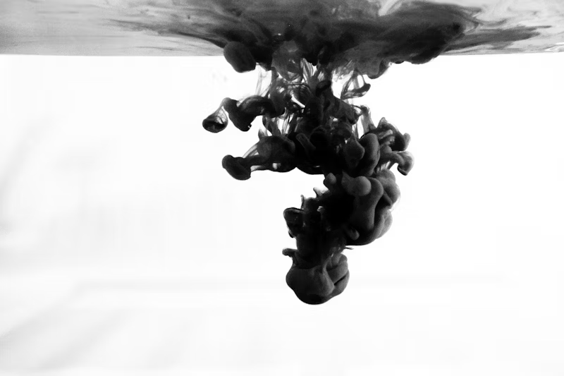 a black drop falling into liquid