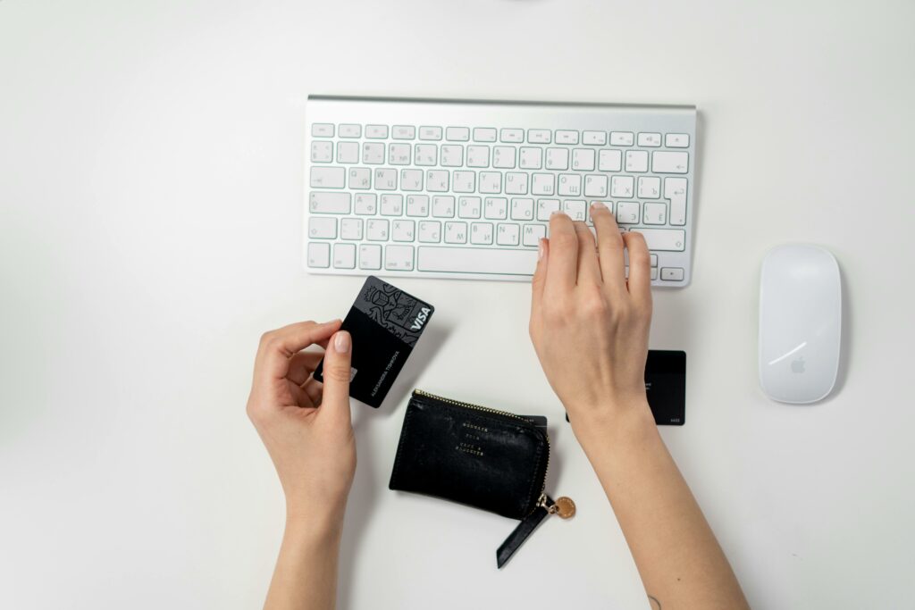 Person holding a bank card while typing on a keyboard
