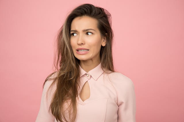 woman experiencing stroke symptom, pink background