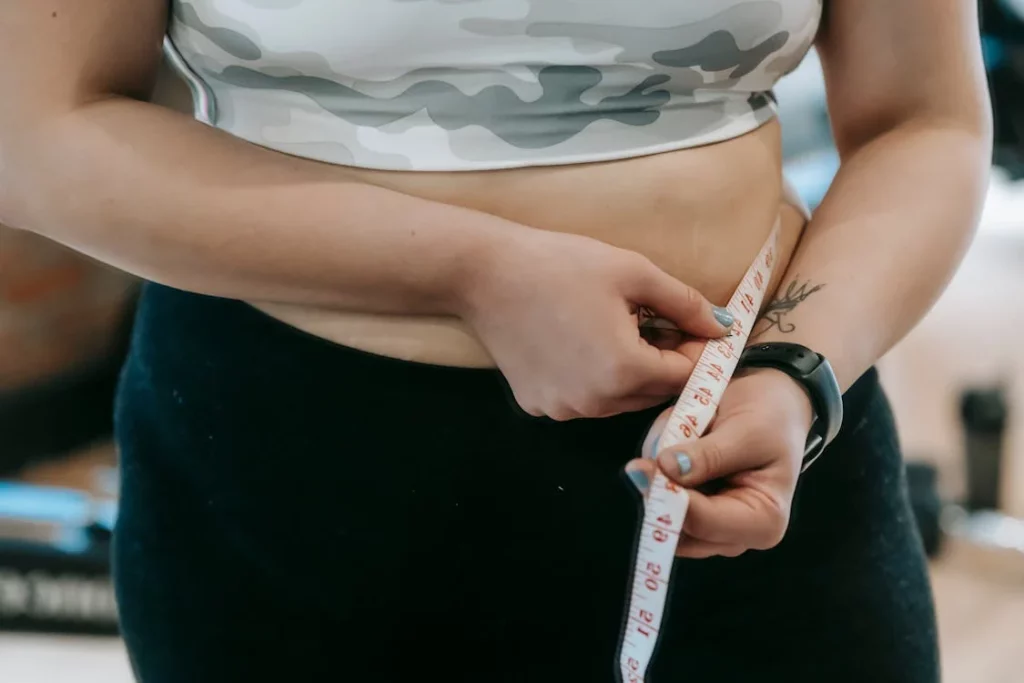 woan using measuring tape, to measure her waistline
