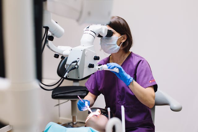 dentist looking into mouth of patient using dental equipment