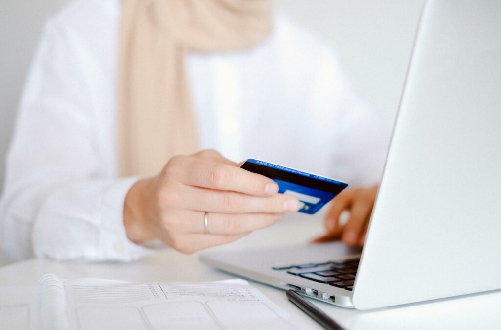 Person holding a bank card while typing on a laptop