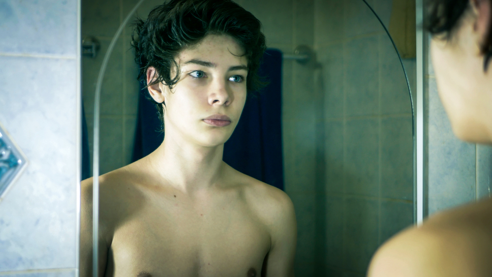 young boy standing in front of mirror in the morning
