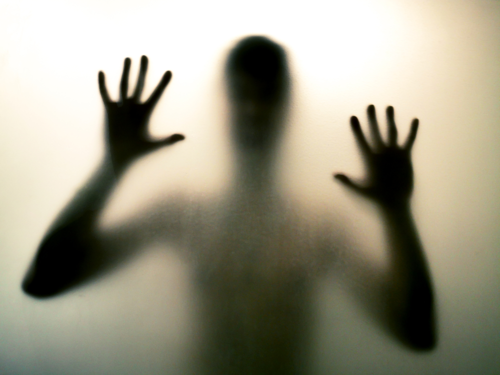 Horror man behind the matte glass in black and white. Blurry hand and body figure abstraction. Halloween background. Murder concept. Criminal concpet.