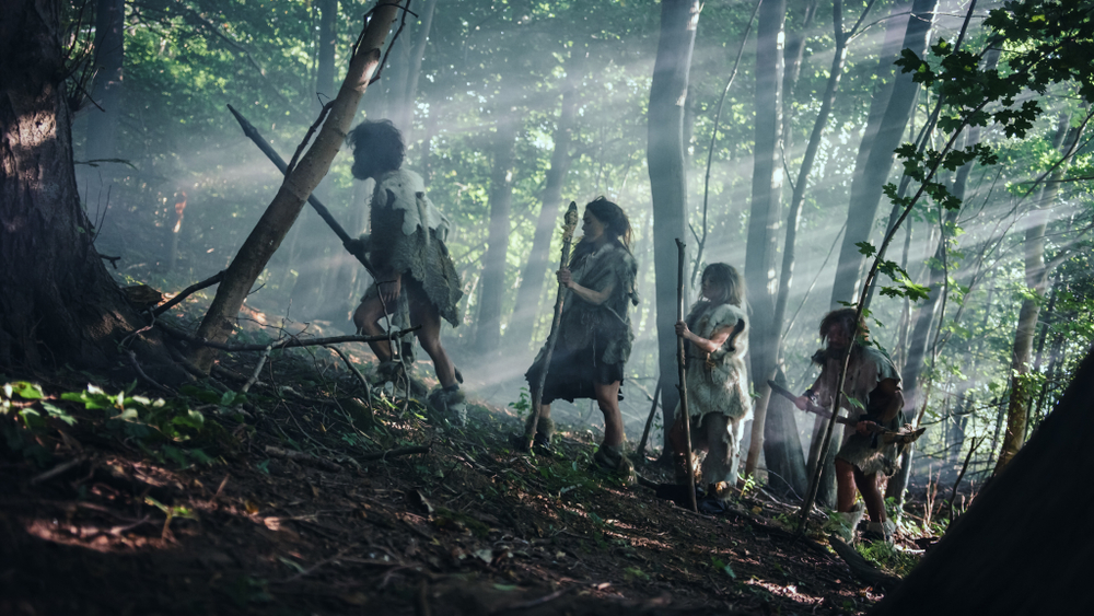 Tribe of Hunter-Gatherers Wearing Animal Skin Holding Stone Tipped Tools, Explore Prehistoric Forest in a Hunt for Animal Prey. Neanderthal Family Hunting in the Jungle or Migrating for Better Land
