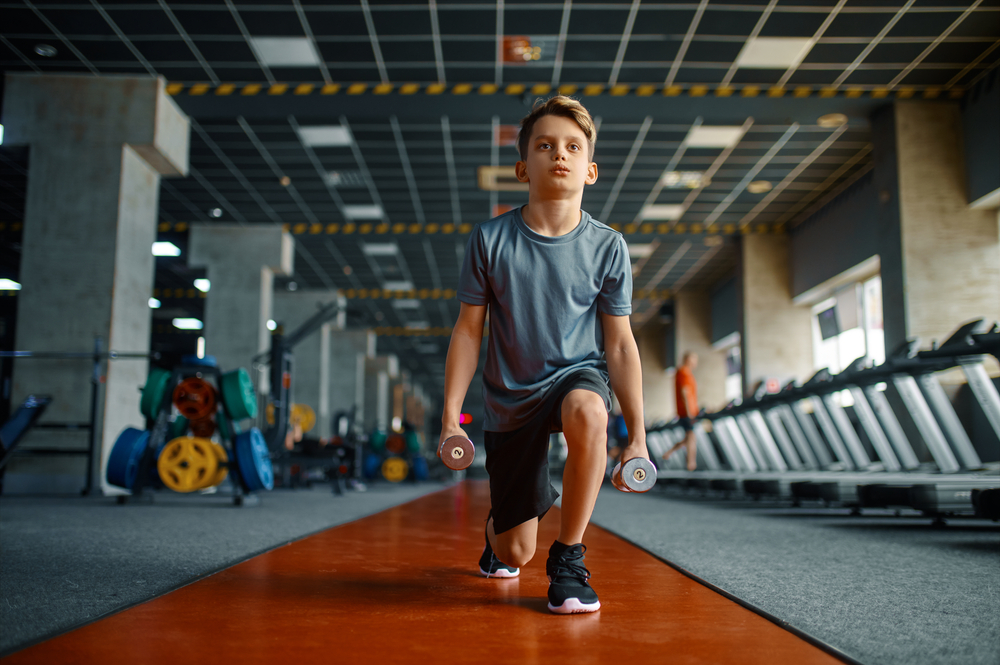 Boy doing exercise with dumbbells in gym
