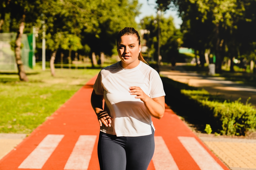 Excess weight gain, overweight asian young woman touching stomach wearing fit body clothes, dissatisfied about her body shape from fat around waist. Obese getting belly fat, diet, weight loss concept
