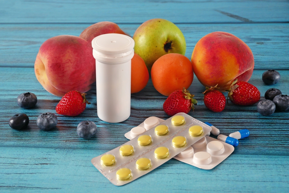 fresh natural fruits vs pills. Natural vitamin in fruits vs synthetic vitamin in pills. Choice between natural and synthetic way of health care. Alternative medicine. Closeup
