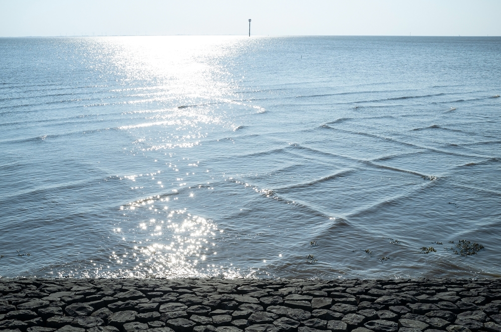 Sea with unusual square waves near the shore, against the blue sky. Beautiful spring landscape.
