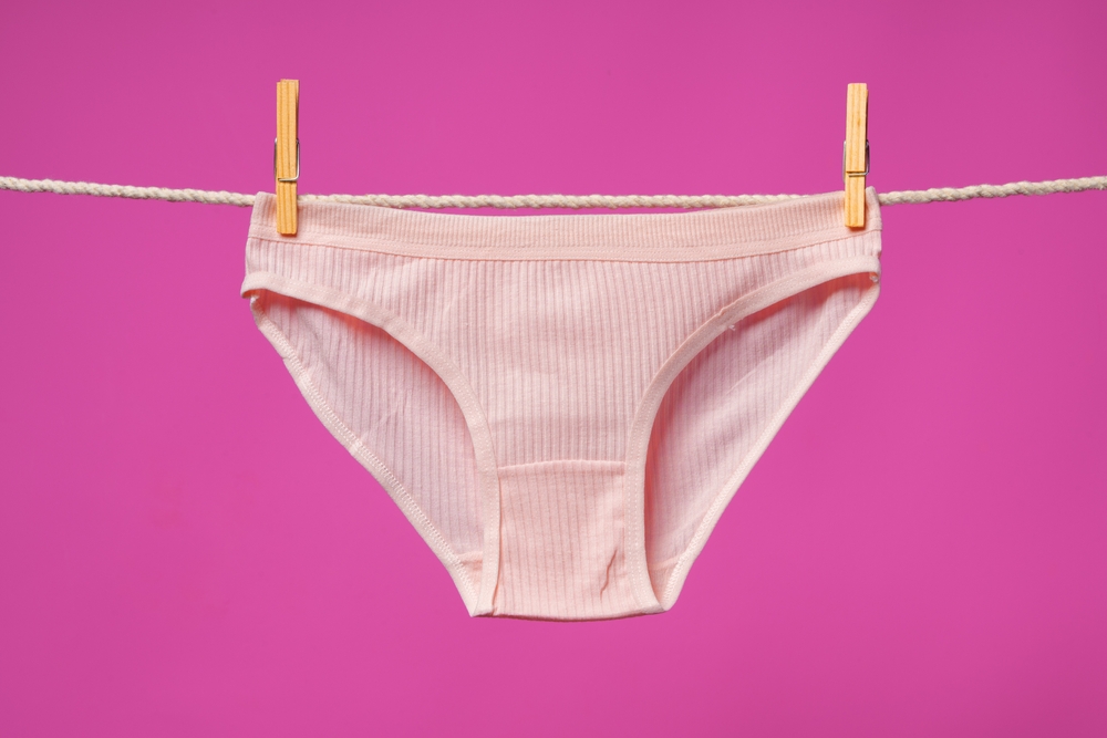 Female panties hanging on rope against pink studio background