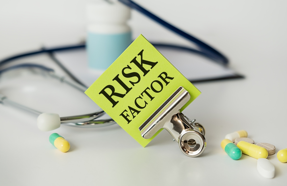 Paper with text risk factor on white background with stethoscope and pills