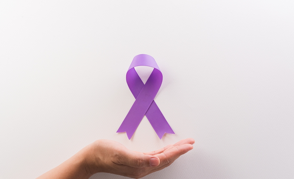 Hand holding purple ribbon on white background for supporting World Cancer Day campaign on February 4.