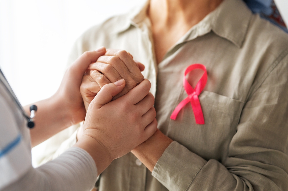 Pink ribbon for breast cancer awareness. Female patient listening to doctor in medical office. Support people living with tumor illness.