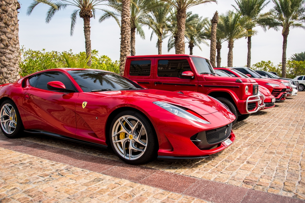 Dubai, United Arab Emirates – February 10, 2021: A red Ferrari car next to other luxurious stylish modern cars parked near the hotel in Dubai.
