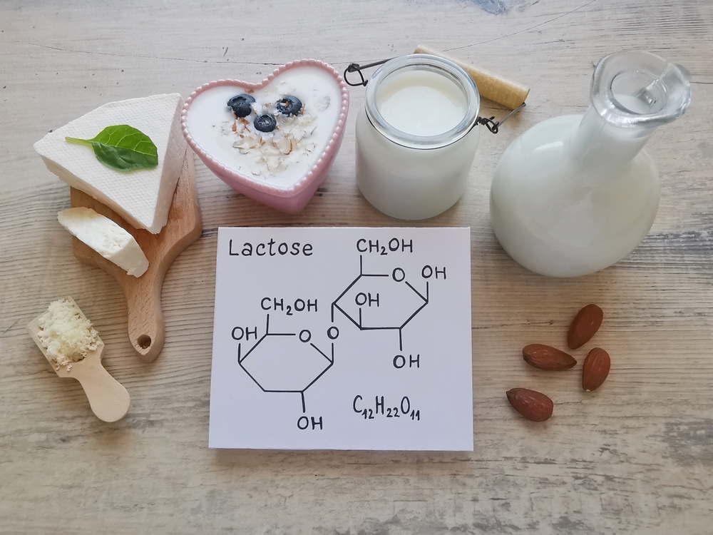 Foods high in lactose with structural chemical formula of lactose. Lactose is a disaccharide, milk sugar molecule. Assortment of dairy products rich in lactose. Cow milk, yogurt, cheese.
