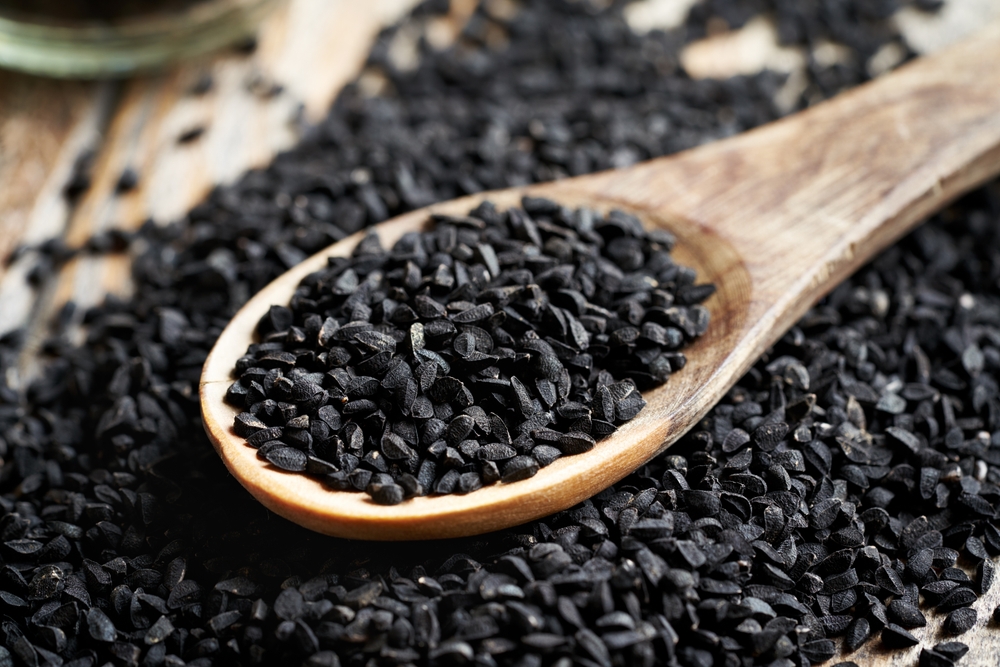 Black cumin or Nigella sativa seeds on a wooden spoon on a table