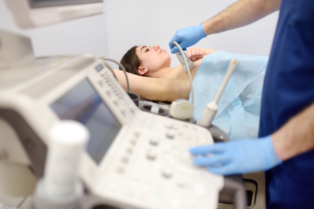 Mammologist doctor examines a woman breasts and lymph nodes using ultrasound. Mammography and ultrasound scanning are main methods of instrumental diagnosis of mammary glands. Breast cancer awareness