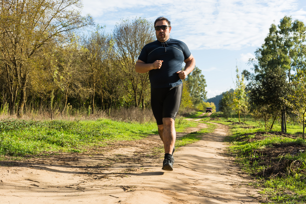 Big belly man jogging - exercising, doing cardio in the park - slightly overweight loosing weight - Young overweight man running outdoors - Fat man running
