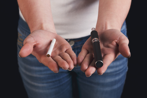 Alternative smoking background. Unrecognizable woman holding vape and tobacco cigarette in hands. Making choice, safe smoking and vaping concept