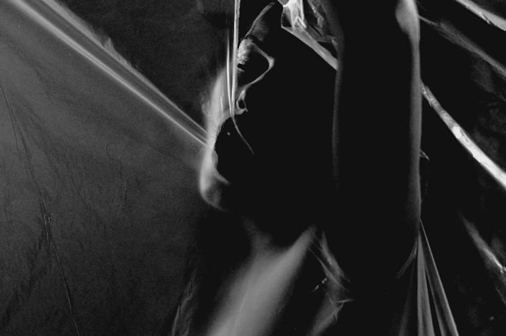 A woman in the shadows raises a sheet, embodying a powerful moment of passion and fulfillment.