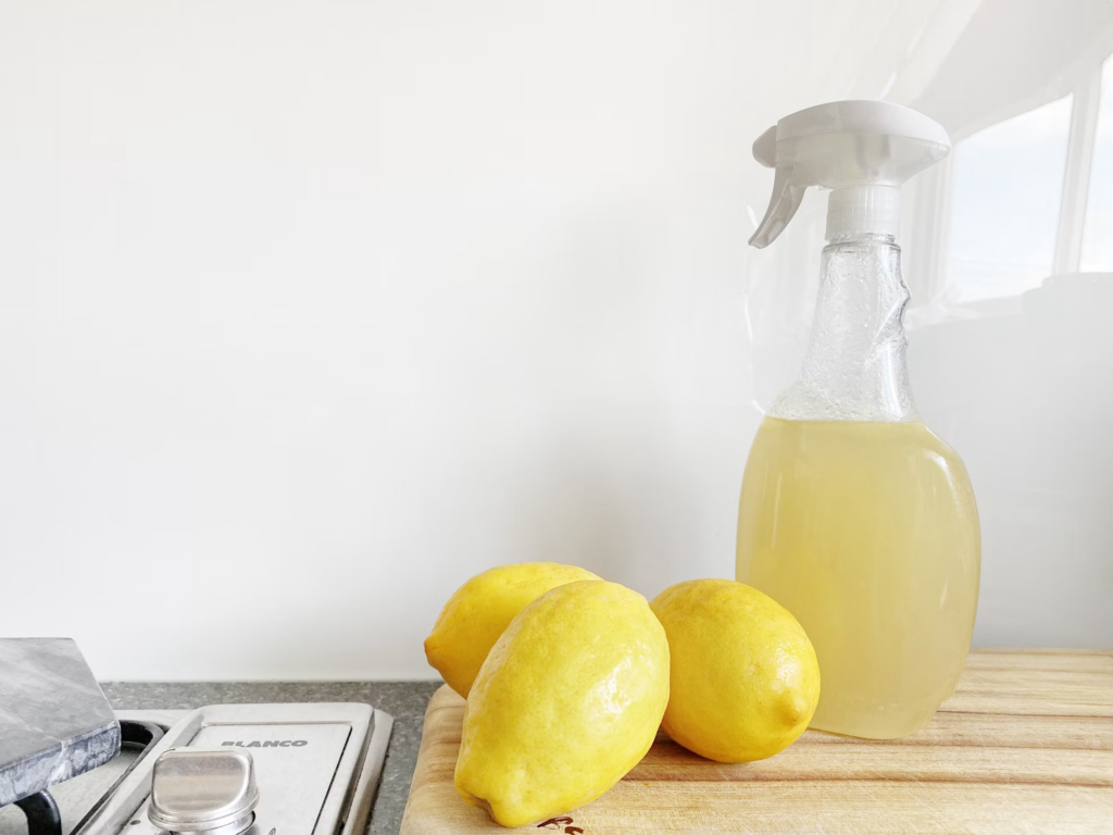 A lemon alongside a bottle of lemon cleaner on a cutting board, emphasizing safe cleaning solutions for a healthy home.