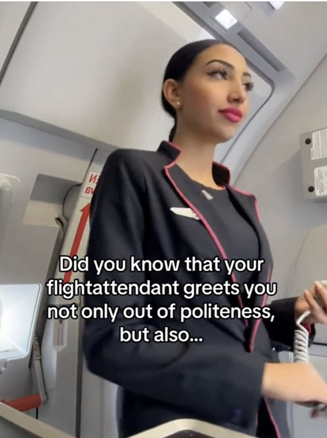 Female cabin crew member standing in front of the exit of an airplane.