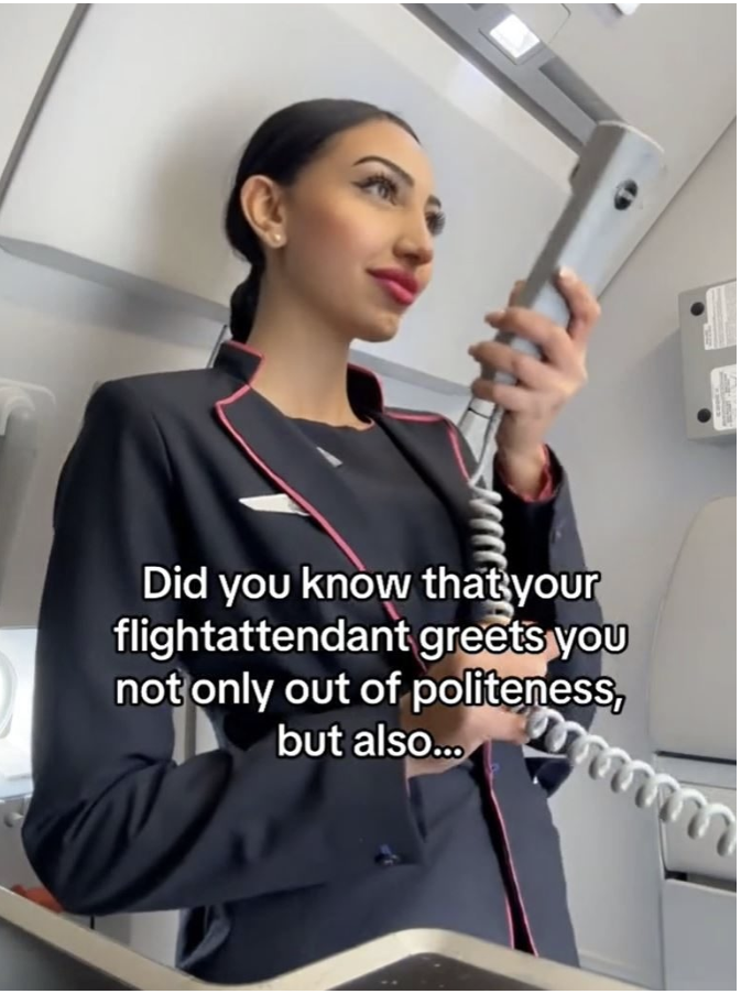 Female cabin crew member standing in front of the exit of an airplane. Preparing to make an announcement.