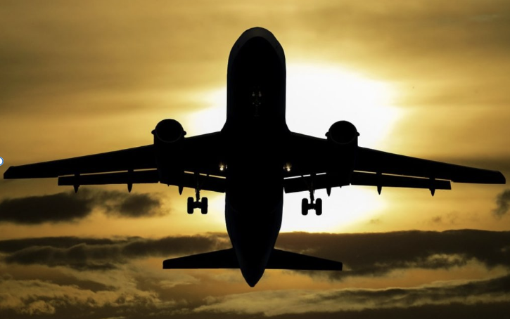 Airplane flying. Sunset, sky, and clouds in the background.