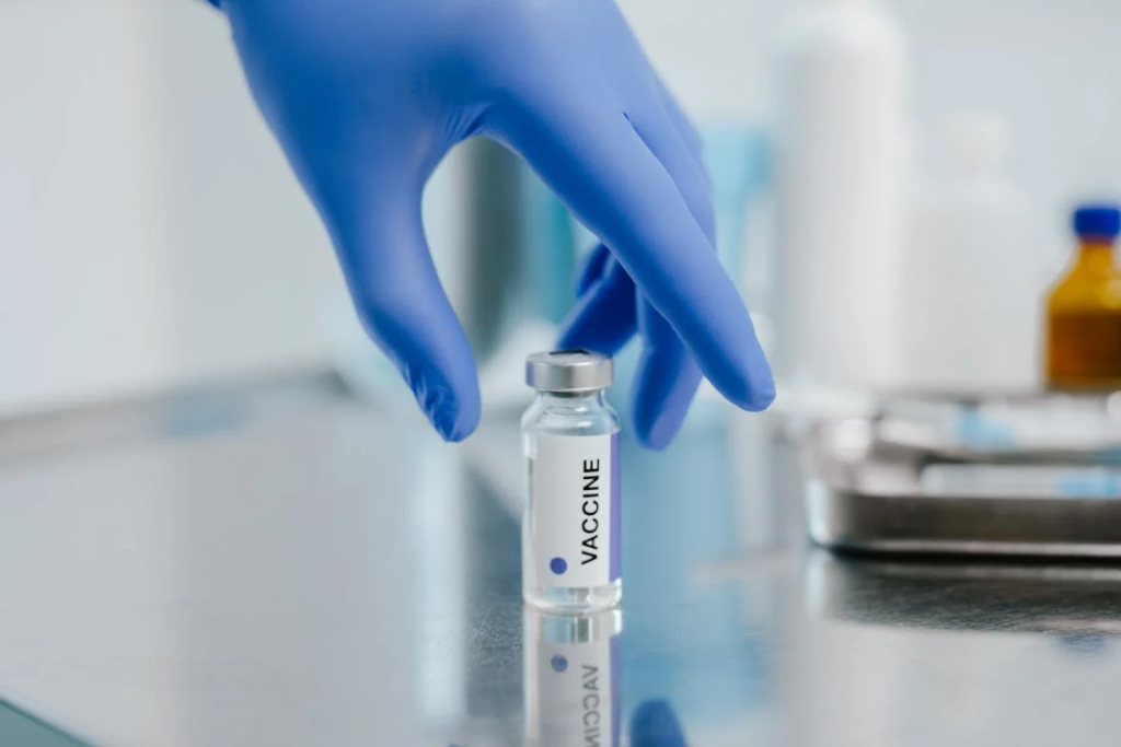 A Hand with Blue Glove Near the Vaccine Via;l