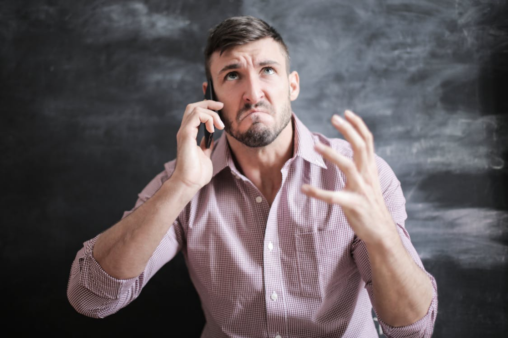A man with an angry expression speaks on his cell phone, conveying frustration during a conversation.