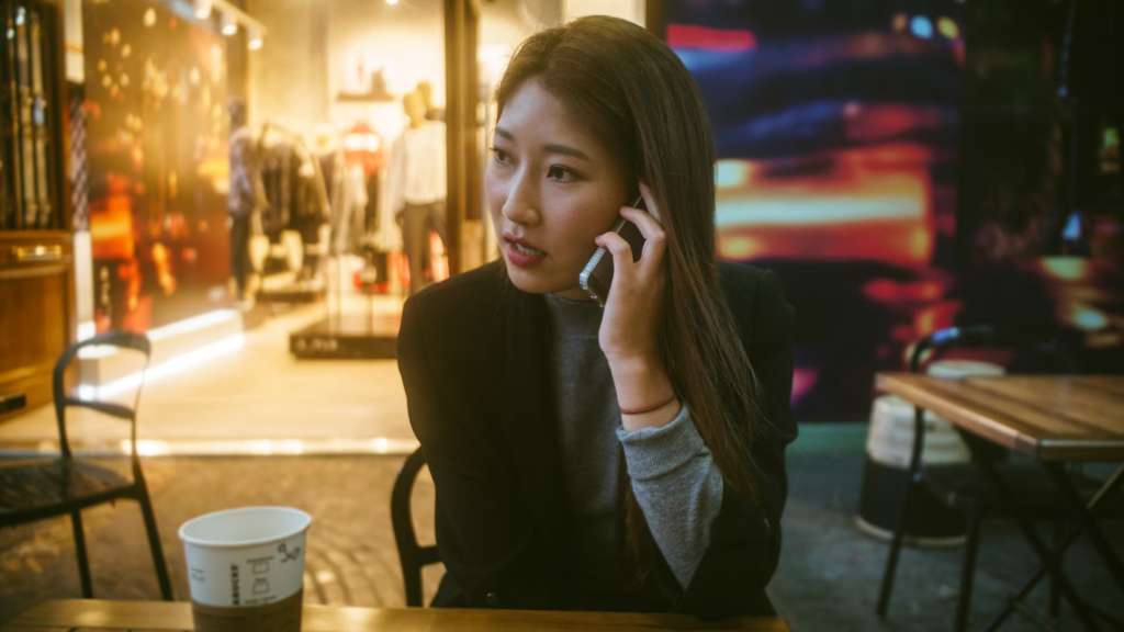 An annoyed woman at a table, speaking on her phone, highlighting the rule that debt collectors should not call during dinner.